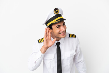 Wall Mural - Airplane pilot over isolated white background listening to something by putting hand on the ear