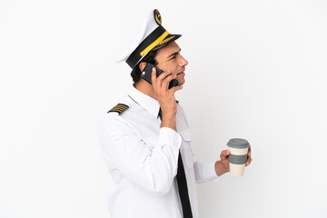 Wall Mural - Airplane pilot over isolated white background holding coffee to take away and a mobile