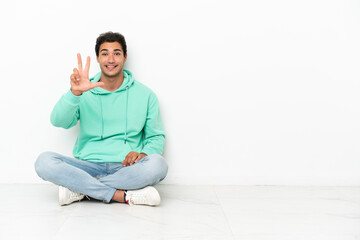 Wall Mural - Caucasian handsome man sitting on the floor happy and counting three with fingers