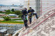 © chitsanupong - Male two worker inspection wearing safety first harness rope safety line working at a high place on tank roof spherical