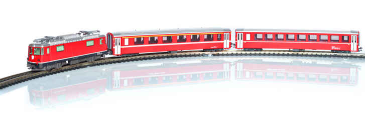 Scale toy model of red train isolated on white reflective background