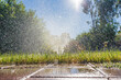 © Austockphoto - Low angled view of a garden sprinkler send a spray of water over green grass
