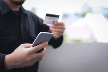 Wall Mural - Concept of online payment via credit card. Businessman uses a mobile phone to pay with a credit card through a banking application.