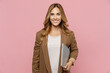 © ViDi Studio - Young happy fun successful employee business woman 30s she wear casual brown classic jacket hold closed laptop pc computer look aside on workspace area isolated on plain pastel light pink background.