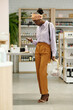 © pressmaster - Young African American female consumer in smart casualwear choosing beautycare products while standing in front of display