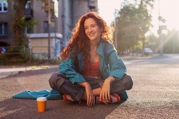 Wall Mural - Young red haired woman sitting on the street in city