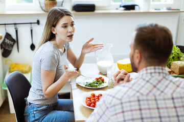 Wall Mural - Frustrated young woman arguing with her husband at dining table