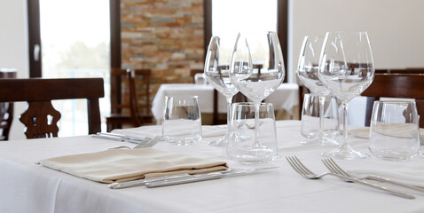 Restaurant table set up with tableware and wine glass. Interior of italian restaurant