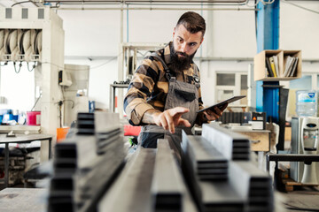 An industry worker checking on bus construction in vehicle production factory.