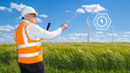 Engineer works at wind farm. Man technician with wind turbines. Worker in uniform power plant engineer. Man stretches hand towards windmills. World Energy consumption concept. Wind turbines in field