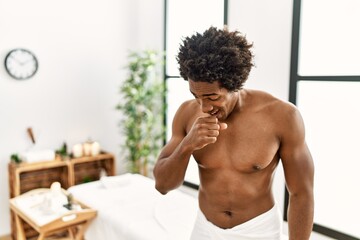 Poster - Young african american man shirtless wearing towel standing at beauty center feeling unwell and coughing as symptom for cold or bronchitis. health care concept.