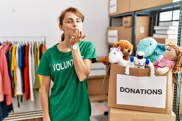 Sticker - Beautiful caucasian woman wearing volunteer t shirt at donations stand looking at the camera blowing a kiss with hand on air being lovely and sexy. love expression.