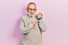 Handsome Senior Man With Beard Wearing Casual Sweater And Glasses In Hurry Pointing To Watch Time, Impatience, Looking At The Camera With Relaxed Expression