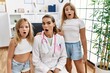 Pediatrician woman working at the clinic with two little girls scared and amazed with open mouth for surprise, disbelief face