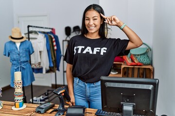 Wall Mural - Young hispanic woman working as staff at retail boutique smiling pointing to head with one finger, great idea or thought, good memory