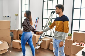 Poster - Young latin couple smiling happy standing with hands together at new home.