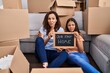 © Krakenimages.com - Young mother and daughter sitting on the floor at new home clueless and confused expression. doubt concept.