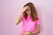 © Krakenimages.com - Young caucasian woman standing over pink background worried and stressed about a problem with hand on forehead, nervous and anxious for crisis