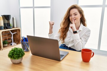 Poster - Young caucasian woman working at the office using computer laptop asking to be quiet with finger on lips pointing with hand to the side. silence and secret concept.