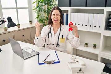 Canvas Print - Hispanic doctor woman holding support red ribbon annoyed and frustrated shouting with anger, yelling crazy with anger and hand raised