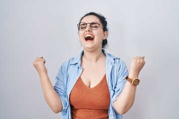 Sticker - Young modern girl with blue hair standing over white background very happy and excited doing winner gesture with arms raised, smiling and screaming for success. celebration concept.