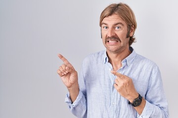 Sticker - Caucasian man with mustache standing over white background pointing aside worried and nervous with both hands, concerned and surprised expression