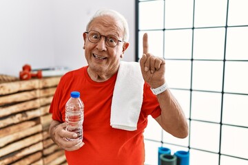 Canvas Print - Senior man wearing sportswear and towel at the gym pointing finger up with successful idea. exited and happy. number one.