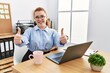 © Krakenimages.com - Young redhead woman working at the office using computer laptop approving doing positive gesture with hand, thumbs up smiling and happy for success. winner gesture.