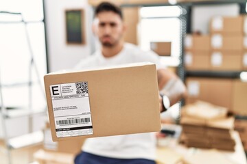 Wall Mural - Young hispanic man working at small business ecommerce holding box depressed and worry for distress, crying angry and afraid. sad expression.