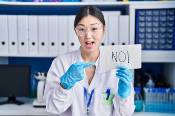 Wall Mural - Chinese young woman working at scientist laboratory holding no banner smiling happy pointing with hand and finger