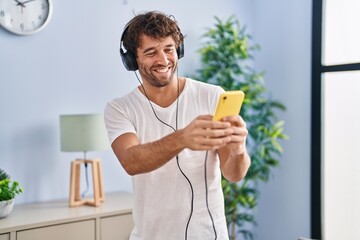 Canvas Print - Young man listening to music standing at home