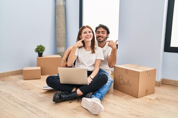 Canvas Print - Young couple using laptop at new home smiling cheerful showing and pointing with fingers teeth and mouth. dental health concept.