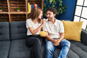 Poster - Man and woman smiling confident eating chips potatoes at home