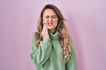 Poster - Young caucasian woman standing over pink background touching mouth with hand with painful expression because of toothache or dental illness on teeth. dentist