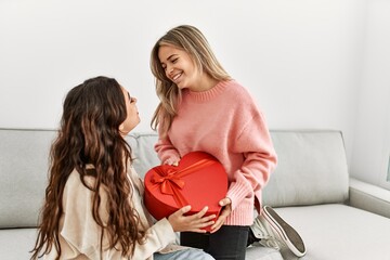 Poster - Young woman surprising her girlfriend with valentine gift at home.