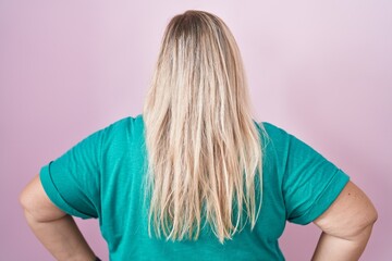 Sticker - Caucasian plus size woman standing over pink background standing backwards looking away with arms on body