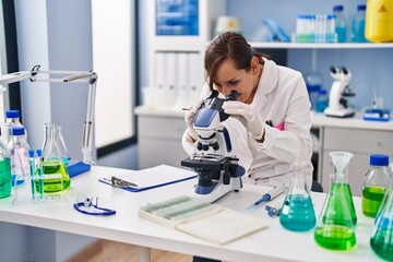 Poster - Middle age woman wearing scientist uniform using microscope at laboratory