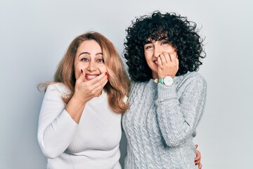 Poster - Middle east mother and daughter wearing casual clothes laughing and embarrassed giggle covering mouth with hands, gossip and scandal concept