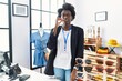 African young woman working as manager at retail boutique mouth and lips shut as zip with fingers. secret and silent, taboo talking