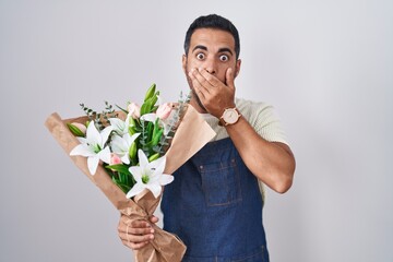 Wall Mural - Hispanic man with beard working as florist shocked covering mouth with hands for mistake. secret concept.