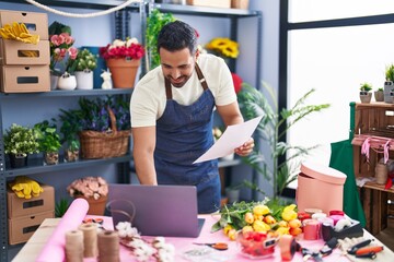 Sticker - Young hispanic man florist using laptop reading paper at florist