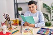 © Krakenimages.com - Young non binary man artist smiling confident reading book at art studio