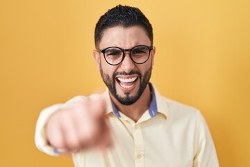 Wall Mural - Hispanic young man wearing business clothes and glasses pointing displeased and frustrated to the camera, angry and furious with you