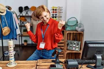 Sticker - Middle age blonde woman working working as manager at retail boutique very happy and excited doing winner gesture with arms raised, smiling and screaming for success. celebration concept.