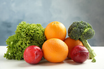 Wall Mural - fresh fruits and vegetables on white table against light blue background