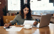 © N Felix/peopleimages.com - Young businesswoman, entrepreneur and coffee shop owner looking overwhelmed going through paperwork. Serious and concerned female cafe manager going through or reading logistics sheet for the month.