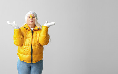 Poster - Ill mature woman with clothespin on light background. Stuffy nose concept