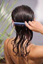 Hair. Beautiful Brunette Woman Brushing Her Wet Hair. Back View Of Woman Hair-brushing With Comb And Using Conditioner. Hair Care. Spa Beauty Model 