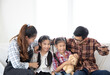 © Aree - Happy Asian  family sitting watching TV in their home