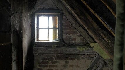 Window in the old house attic, spider web, old traditional wooden residential house with brick walls, mystic mood, Halloween concept, wide handheld shot